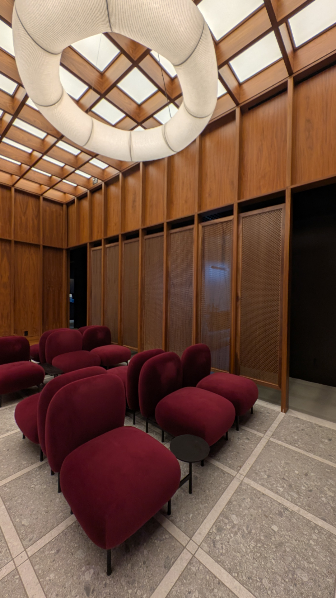Velvet lounge seating beneath a cocooned ring pendant and timber lattice skylight