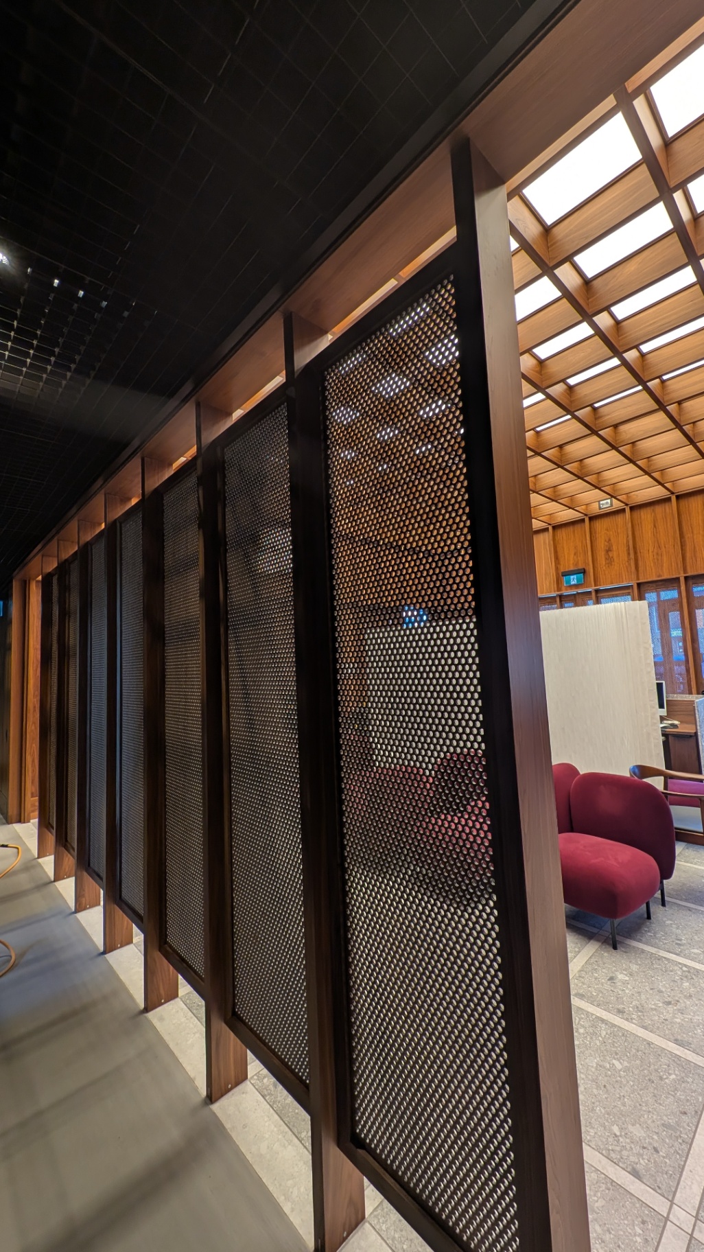 Backlit perforated screens dividing the corridor from the lounge beyond