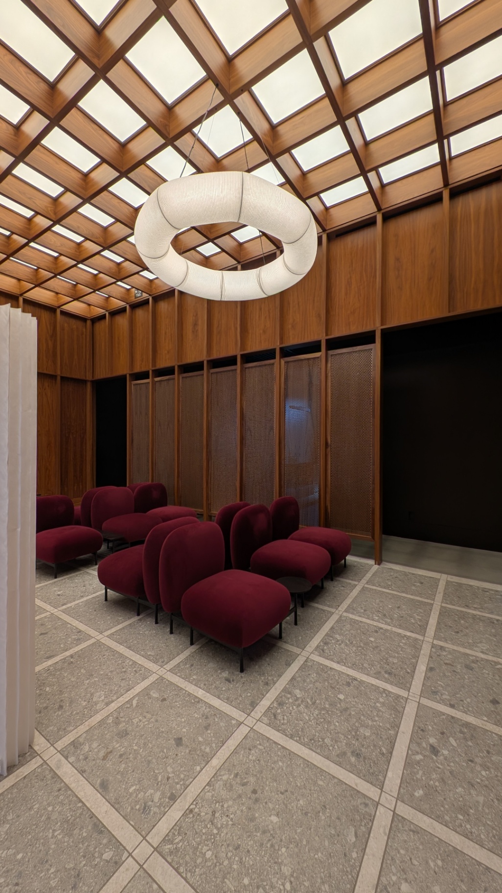 Velvet seating cluster under a diamond-coffered timber ceiling and ring pendant