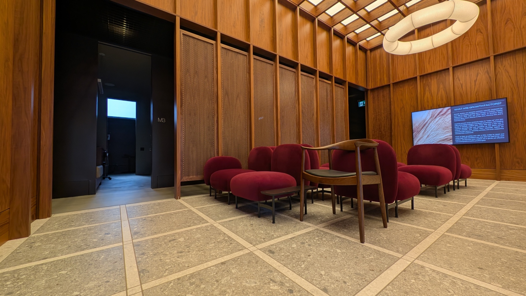 Patient waiting area with bespoke walnut millwork, perforated screens, and a digital education display